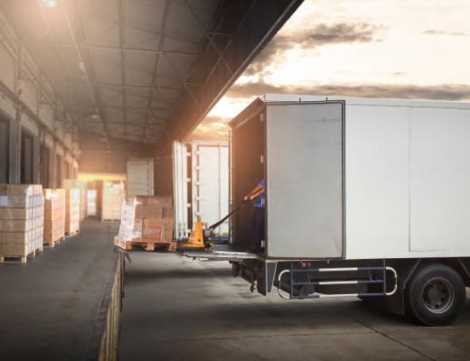Package Boxes on Pallets Loading into Cargo Container. Trucks Parked Loading at Dock Warehouse. Delivery Service. Shipping Warehouse Logistics. Road Freight Truck Transportation.