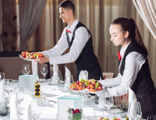 Waiters serving table in the restaurant preparing to receive guests.